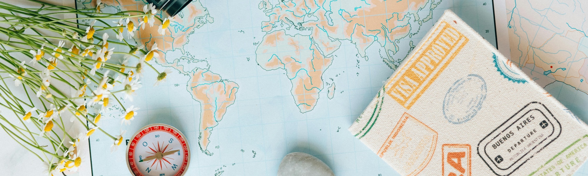 Reiseunterlagen und ein Kompass auf einer Weltkarte
